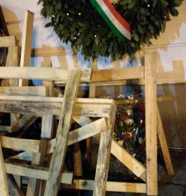 Pancali e travi di legno gettati davanti alla lapide dei partigiani caduti 