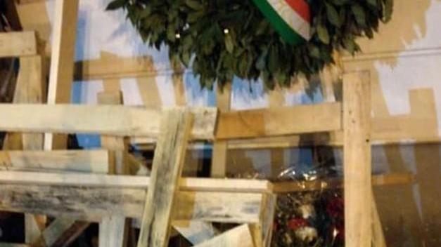 Pancali e travi di legno gettati davanti alla lapide dei partigiani caduti