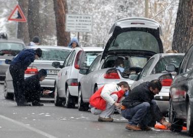 Alcuni automobilisti alle prese con la neve mentre montano le catene   