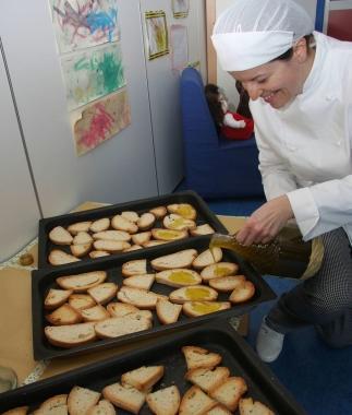 Unaddetta della mensa prepara pane e olio in una scuola (foto darchivio)  