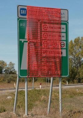 Il cartello oggi coperto che annuncia la trasformazione in autostrada del lotto 1 della Variante 