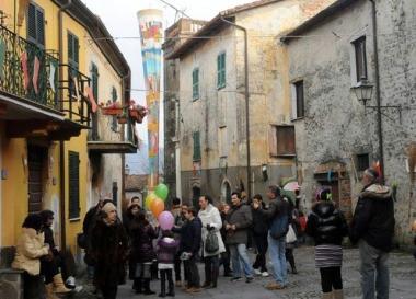 La piazza di Quercia con la maxi calza appesa al campanile e in basso la poetessa Marina Pratici  