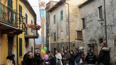 La piazza di Quercia con la maxi calza appesa al campanile e in basso la poetessa Marina Pratici