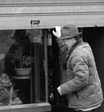 Un negoziante abbassa la saracinesca della propria bottega in centro              