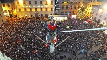 A sinistra la Befana plana dal campanile verso la folla che la attende nella piazza