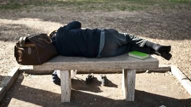 Un senza tetto dorme su una panchina
