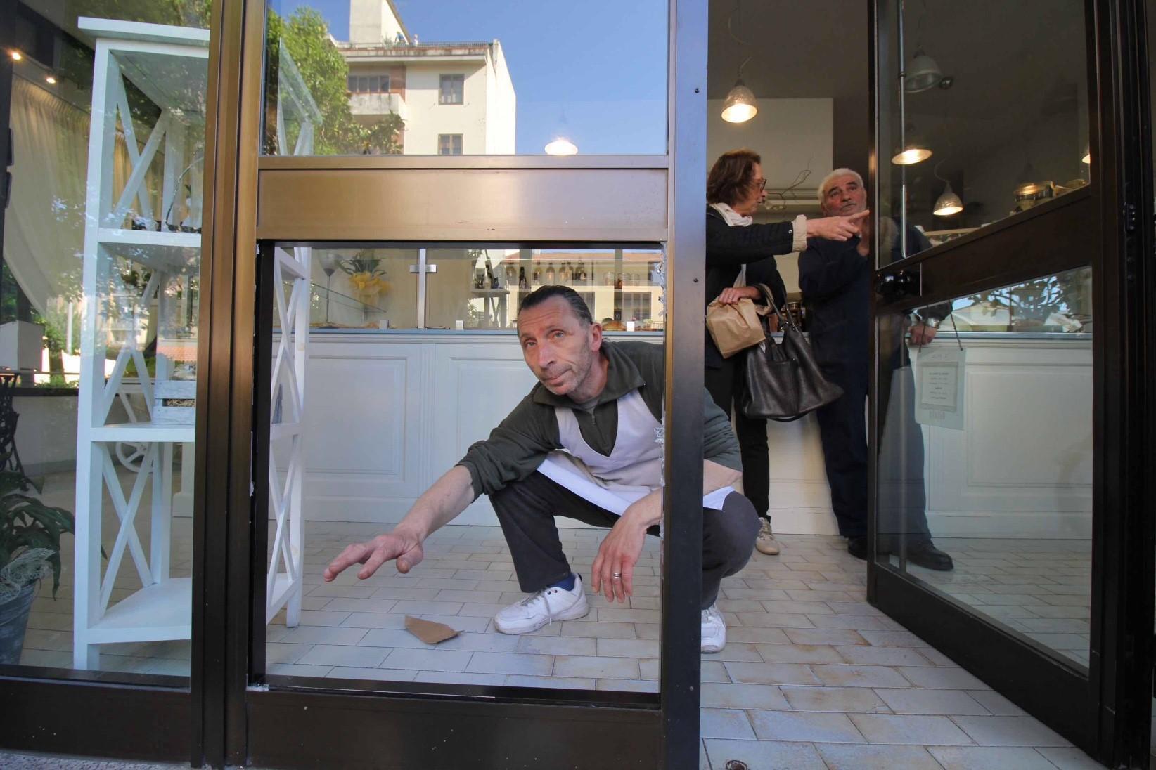 Simone Barchielli, titolare della panetteria Gusto Sì, mostra la vetrata infranta col tombino