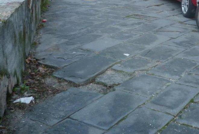 Strada sconnessa, cade una signora