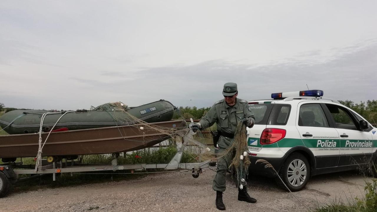Un agente di polizia provinciale con le reti e il gommone sequestrati ai pescatori di frodo