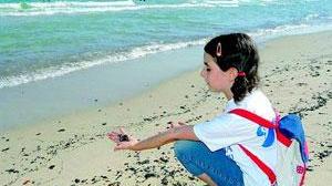Una bambina sulla spiaggia sporca di catrame
