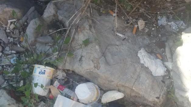 Spazzatura e cocci di bottiglia tra gli scogli lungo il Molo