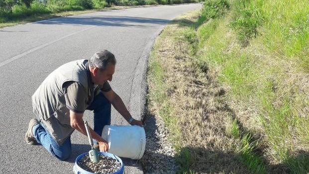 Mario Simoncioli al lavoro per ricoprire una buca sul ciglio della strada