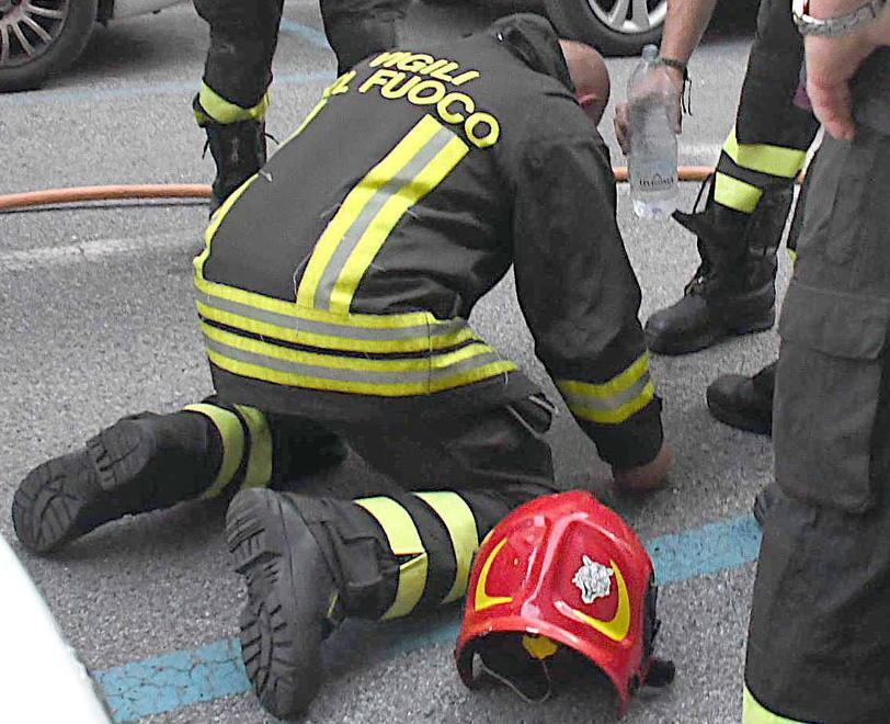 Il vigile del fuoco in ginocchio e la bottiglia d’acqua del collega