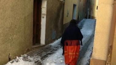 Una donna con l&#146;abito tradizionale e lo scialle per ripararsi dal freddo in una strada del centro coperta di neve (foto Melis) 