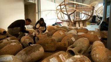 Allestimento della mostra al Ghetto: anfore e sul fondo la nave romana (foto Rosas)