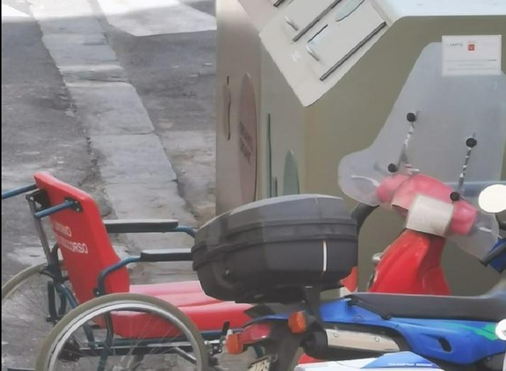 Una sedia a rotelle del pronto soccorso abbandonata accanto al cassonetto Aamps della differenziata in via delle Galere