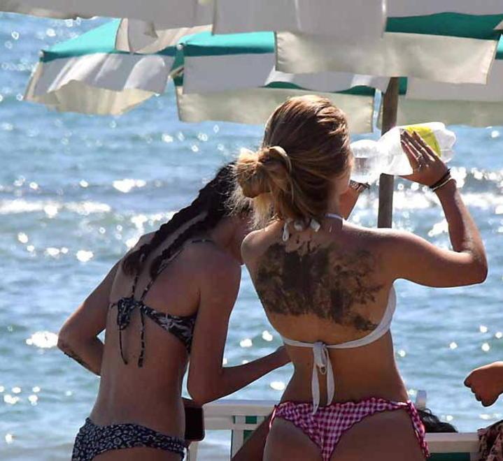 Una ragazza consuma una  bibita in spiaggia