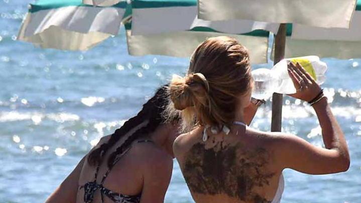 Una ragazza consuma una bibita in spiaggia