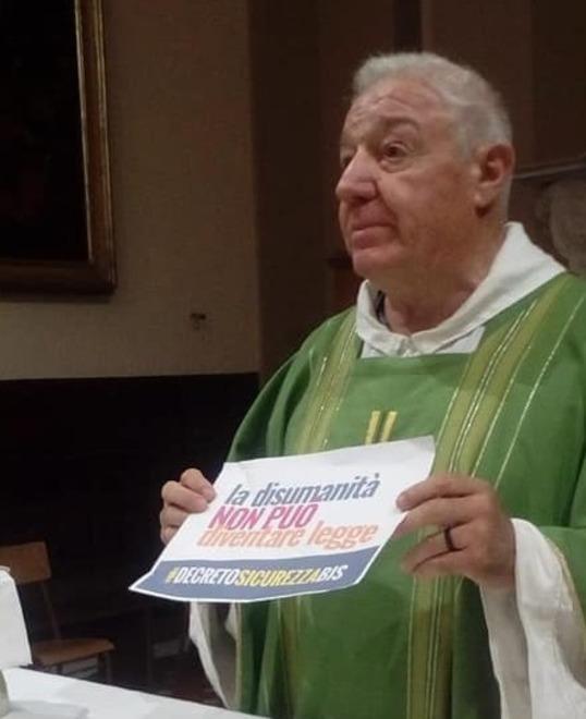 Don Paolo Tofani mentre mostra il cartello anti-decreto