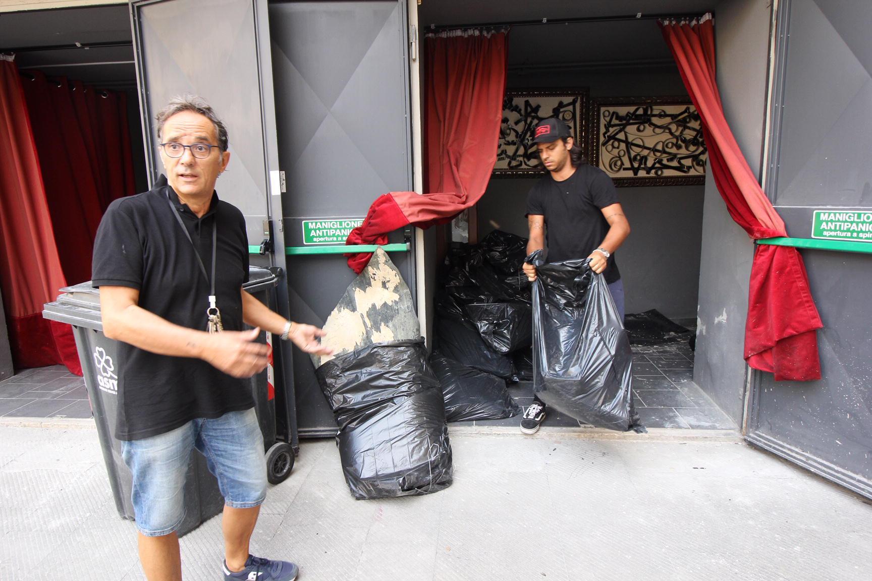 Il gestore del cinema Eden, Eros Ossani, a sinistra, mentre porta fuori sacchi con gli scarti di Pvc
