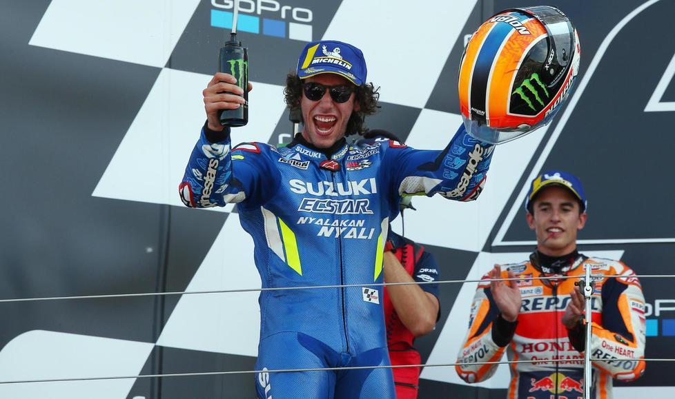 Alex Rins festeggia la vittoria sul podio con, sullo sfondo, il connazionale Marc Marquez infilato nella volata finale