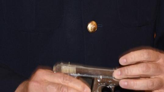 Un agente di polizia mostra una pistola semiautomatica