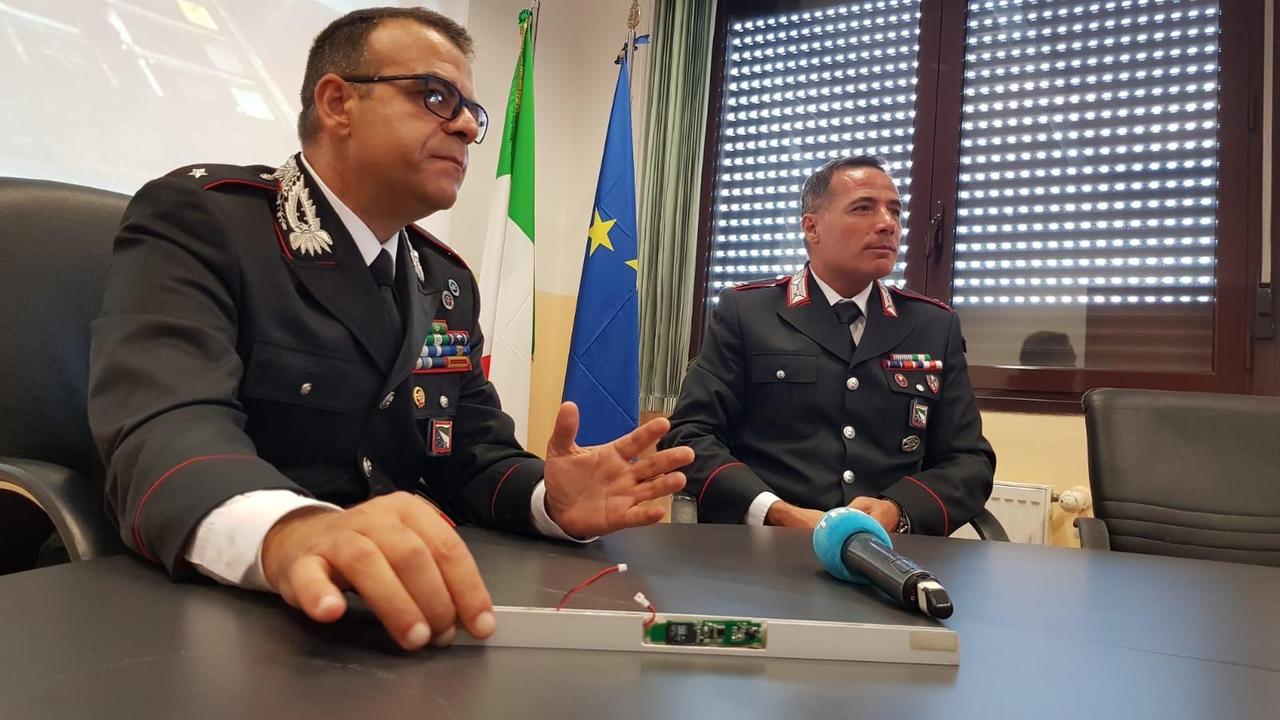 In primo piano, in mano al carabinieire, la mascherina con microcamera utlizzata per carpire i pin dei clienti della banca