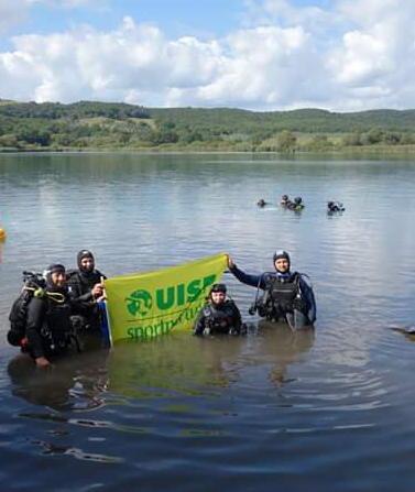 Sub in fondo al lago e bambini con i sacchi 
