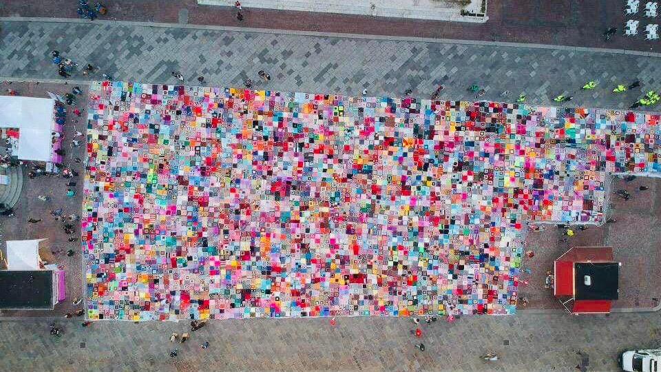 Reggio Emilia, un'immensa coperta colora piazza Prampolini per aiutare la ricerca