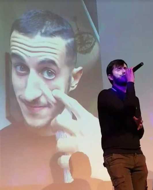 Luca Ricci mentre canta “Mauro Vive” con alle spalle la foto di Cordeschi