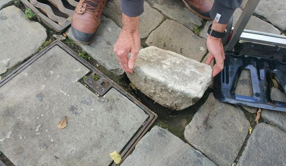 Una pietra è stata rimossa dal selciato del centro e “ricompare” sulla statua 
