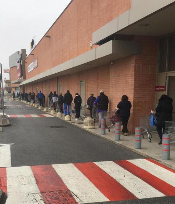 Tutti in fila per la spesa e il carrello viene usato per tenere le distanze