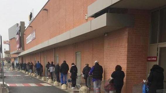 Tutti in fila per la spesa e il carrello viene usato per tenere le distanze