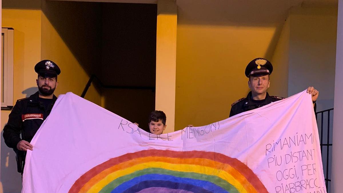 I carabinieri insieme al bambino con lo striscione