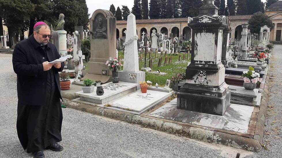 Il vescovo solo nel cimitero prega per tutti i defunti
