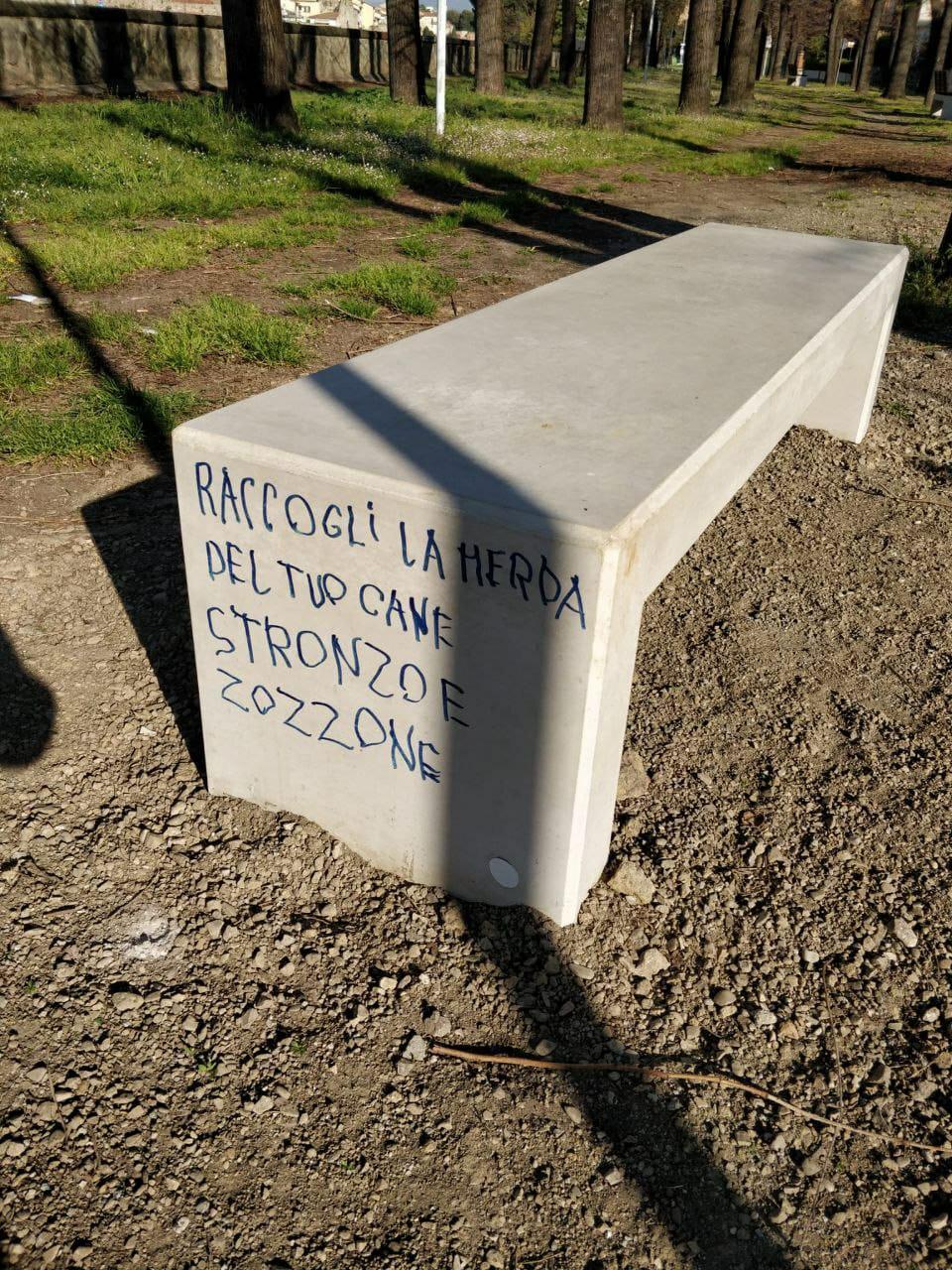 Una delle panchine imbrattata con la scritta contro i proprietari dei cani