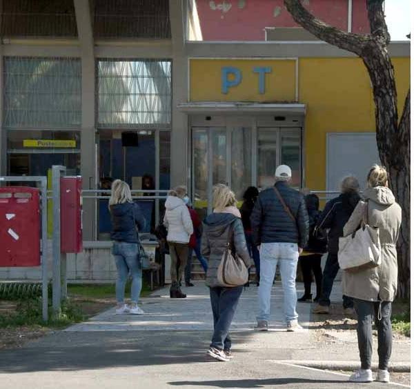 Coda ad un ufficio postale (nella foto d'archivio, Marina di Carrara)
