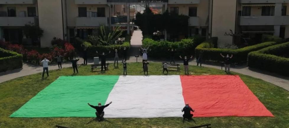 Flash-mob in un condominio, distanti ma vicini abbracciando il tricolore
