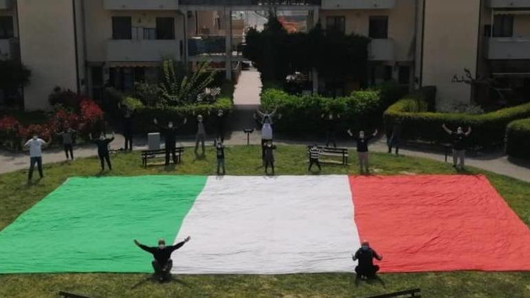 Flash-mob in un condominio, distanti ma vicini abbracciando il tricolore