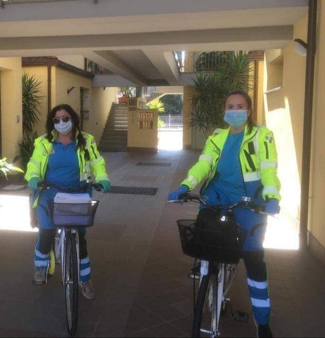 Volontarie consegnano le protezioni in bicicletta