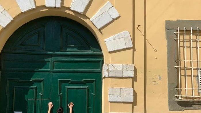 Michele appoggiato al portone chiuso della scuola media "Carducci" in piazza San Ponziano