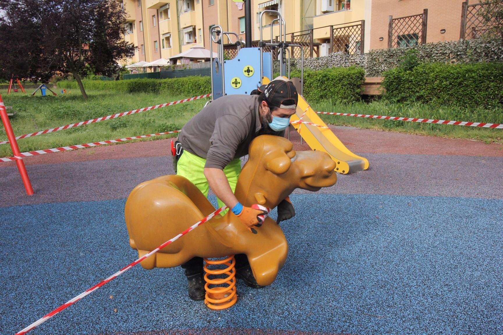 Un operaio di Consiag Servizi mette le fettucce ai giochi per i bambini ai giardini via Beethoven (foto Batavia)