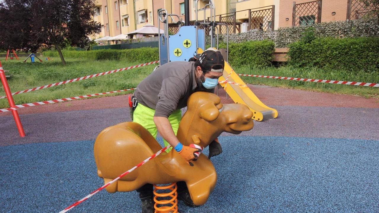 Un operaio di Consiag Servizi mette le fettucce ai giochi per i bambini ai giardini via Beethoven (foto Batavia)