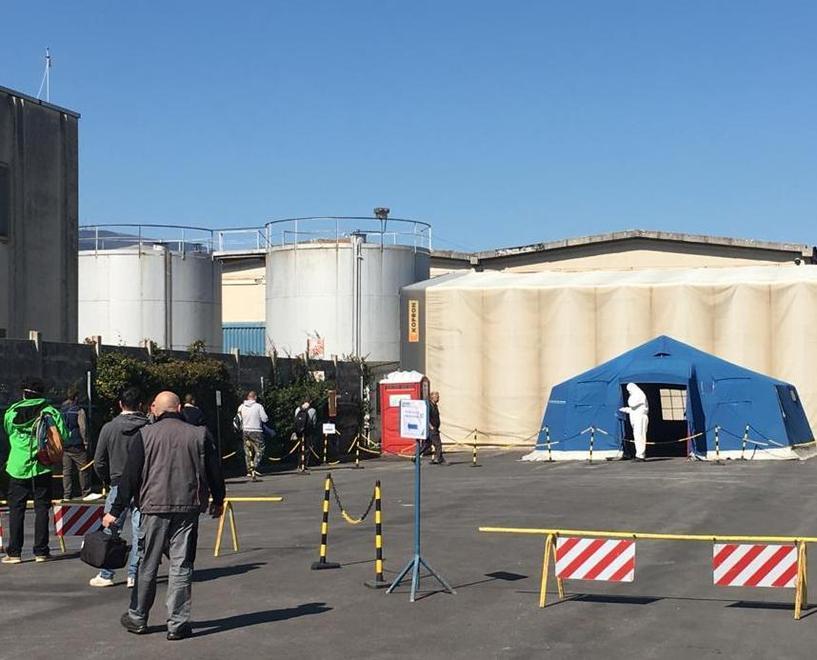 La misurazione della temperatura agli operai prima di entrare in fabbrica; in alto a destra Enrico Dell’Artino