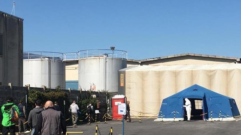 La misurazione della temperatura agli operai prima di entrare in fabbrica; in alto a destra Enrico Dell’Artino