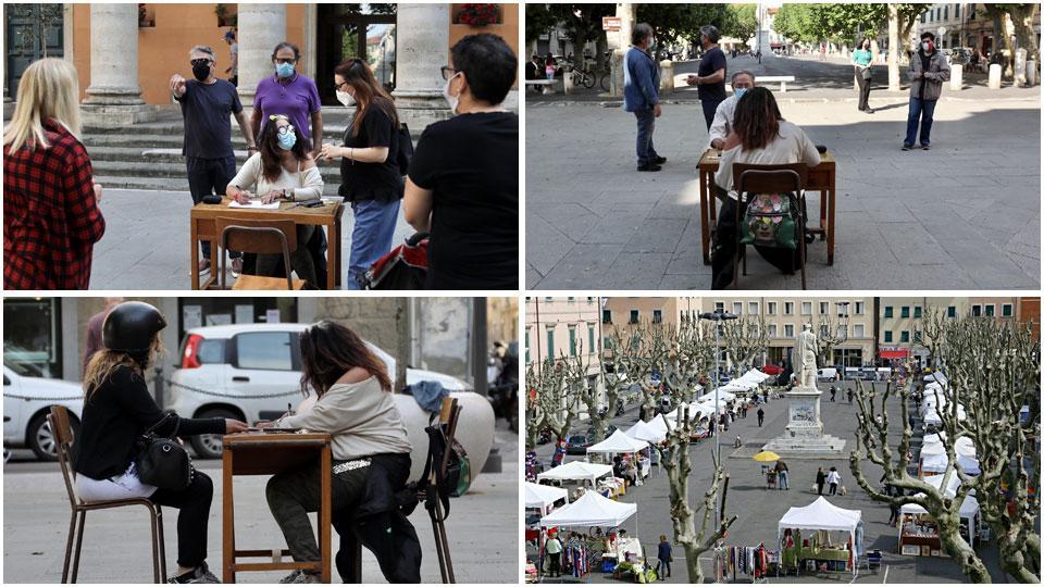 Il banchetto messo nella piazza per la raccolta delle firme, Alcuni residenti a firmare ieri pomeriggio, una ragazza che sta mettendo la sua adesione e piazza XX Settembre con gli stand per una delle iniziative con il mercato che si è svolta di recente