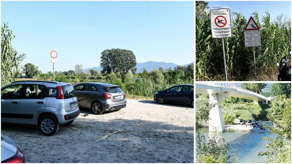 Auto parcheggiate lungo il fiume, i cartelli e le macchine sotto la passerella