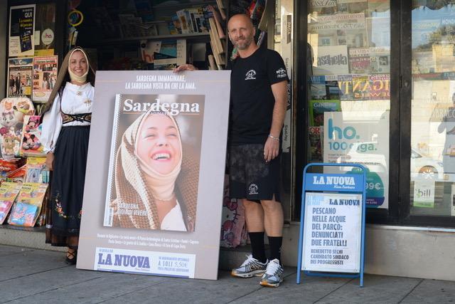 Elisa Murgia nell'abito tradizionale di Ruinas sorride accanto alla luminosa copertina di Sardegna Immaginare ospitata dall'edicolante Emanuele Riu di Porto Torres