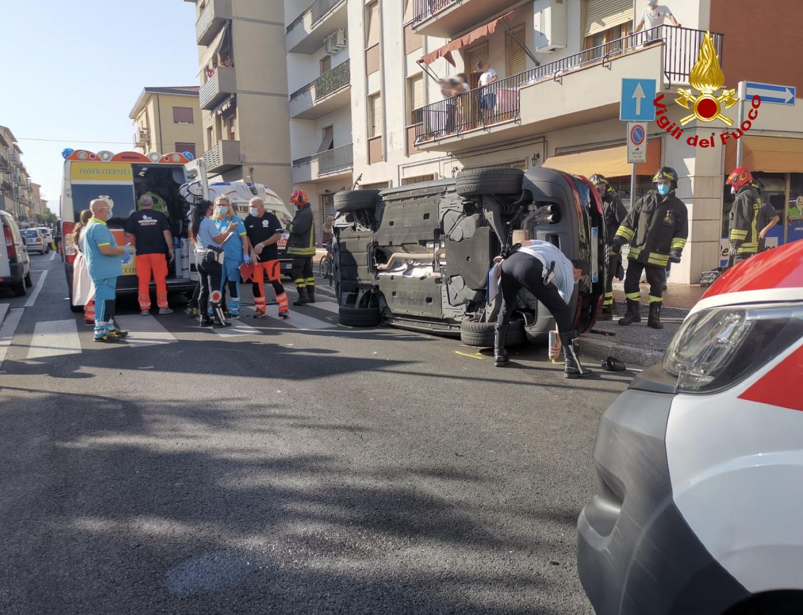 Una delle auto ribaltate in via Ciliani con i soccorritori