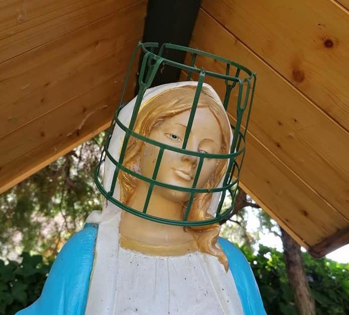 Il cestino lasciato dai vandali sulla statua della Madonna